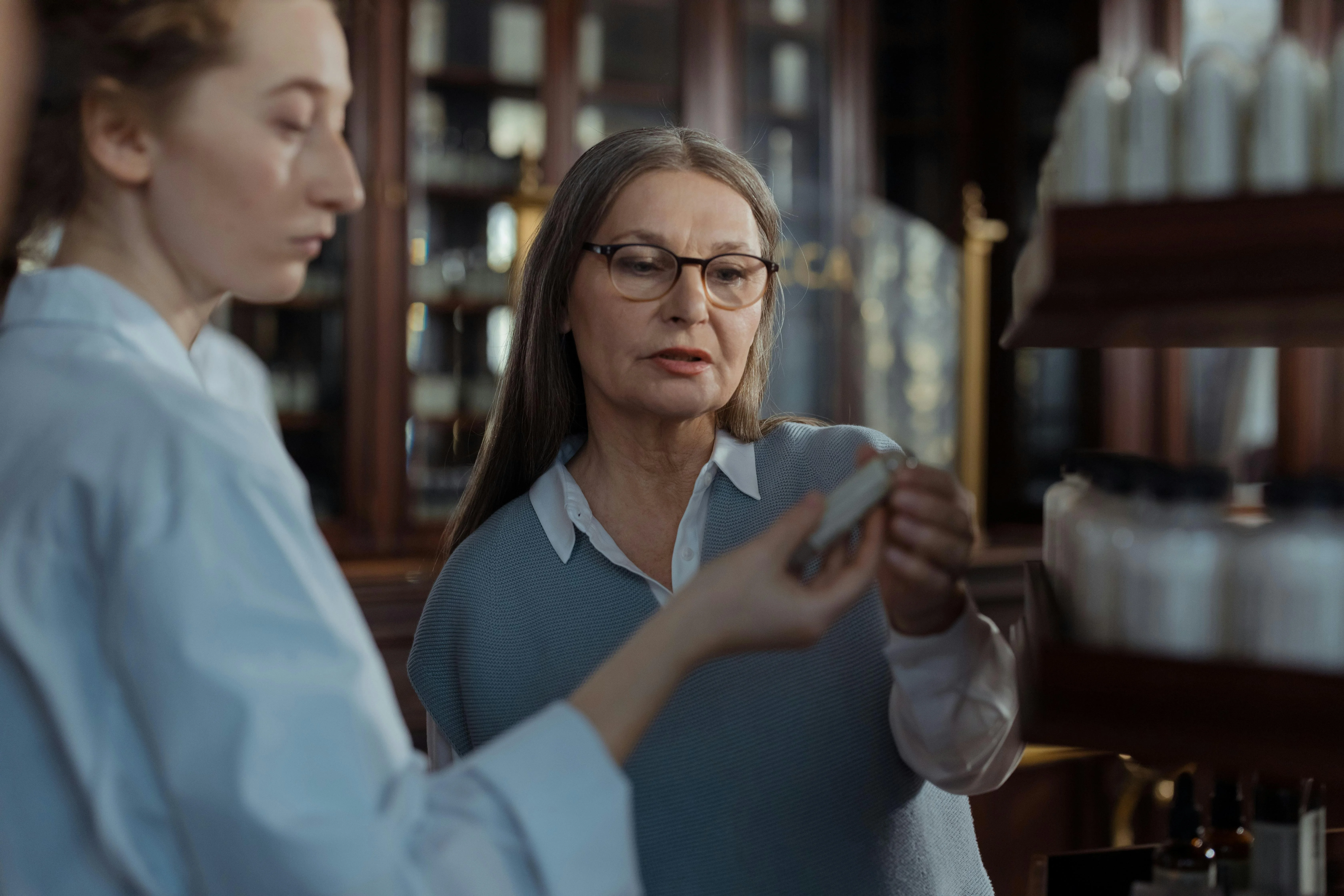 Elderly woman discussing medication options with pharmacist in professional pharmacy setting